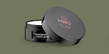 3D mockup of a black Hardworking Gentlemen Clay Pomade plastic container open on a green background.