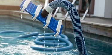 Close-up of pool vacuum equipment being used during a professional pool cleaning visit.