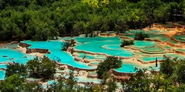 Turquoise lakes of Jiuzhaigou, snow-capped peaks of Huanglong, and a giant panda in a bamboo forest.