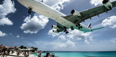 An airplane descending to land over a sandy beach