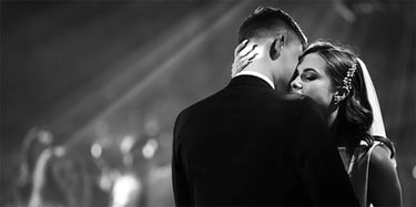 Black and white photo of a bride and groom's romantic first dance at a wedding reception.