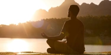 Homme méditant devant un couché de soleil évoquant les problématiques liés à la qualité de vie
