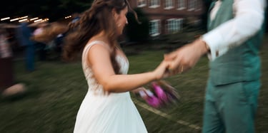 A blurred candid shot of a bride and groom dancing outdoors during their wedding reception.