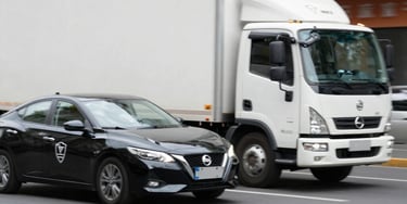 Security personnel escorting a cargo truck on a highway at sunset.
