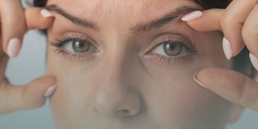 mujer sujetándose los párpados para realzar su mirada