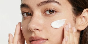 Close-up of a woman gently touching her clear, radiant cheek, smiling softly.