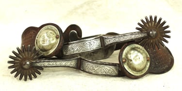Vintage Western spurs with intricate silver detailing.