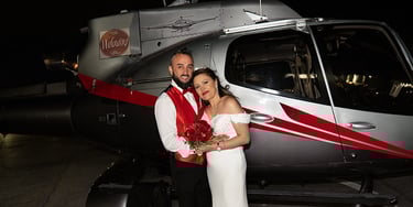 a man and woman standing in front of a helicopter
