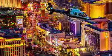 A scenic helicopter tour flying over the glowing neon lights of the Las Vegas Strip at night.