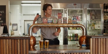 a man is standing behind a bar with beer