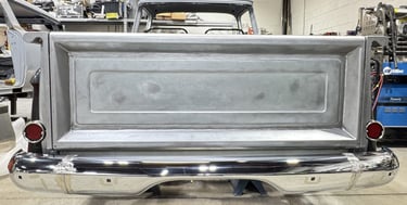 Rear view of a classic vintage truck undergoing metal restoration with a chrome bumper.