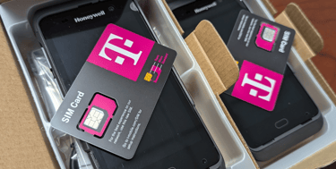 T-Mobile SIM cards sitting on top of new Honeywell mobile handheld scanners in boxes.