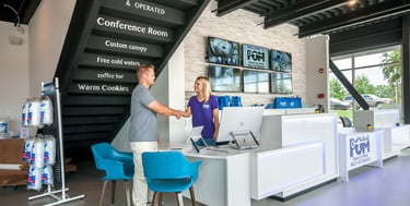 A customer shaking hands with a staff member at a modern POM Self-Storage reception desk office.
