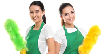 two women in green aprons holding a mop and cleaning supplies