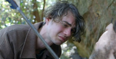 a man in a brown jacket is holding a sword