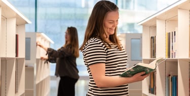 Lehdistökuva tytöistä lukemassa kirjaa Oodi kirjastossa Helsingissä