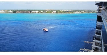 Navio de cruzeiro chegando a George Town, Grand Cayman, com o mar azul-turquesa cristalino ao fundo.