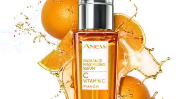 Avon Anew Vitamin C Radiance Maximising Serum bottle with splashing citrus liquid and fresh orange slices.