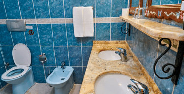 Baño con cerámicas antiguas azules y tope de granito con lavamanos bajo tope.