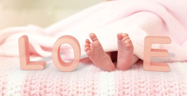 Die Füße eines Babys liegen auf einer Decke mit dem Wort Liebe.