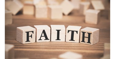 Wooden alphabet blocks spelling the word FAITH on a rustic brown surface.