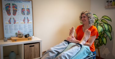 femme assise dans un cabinet pose les mains sur les pieds d'une personne allongée
