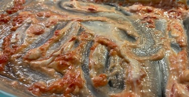 Empty glass baking dish with leftover creamy tomato sauce residue after a homemade meal.