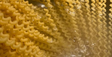 Spiral fusilli bucati pasta noodles boiling in a pot of hot water on a stove