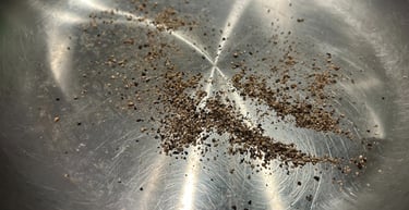Freshly ground black pepper seasoning inside a shiny stainless steel skillet or pan.