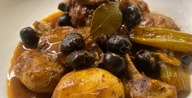 Slow-cooked rabbit stew with black olives, potatoes, celery, and bay leaf in a savory brown sauce.