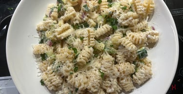 Creamy radiatori pasta with zucchini and parmesan cheese served in a white bowl.