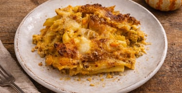 Baked pumpkin pasta casserole with melted cheese and golden crust on a rustic plate.