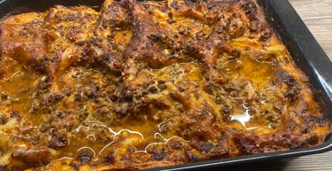 Freshly baked homemade beef lasagna with melted cheese and rich tomato sauce in a black baking dish.