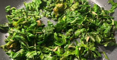 Fresh chopped green kale sautéing in a nonstick frying pan with garlic.