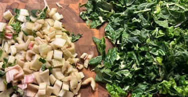 Chopped fresh Swiss chard leaves and diced stems on a wooden cutting board for meal prep.
