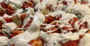 Baked stuffed pasta shells topped with red tomato sauce and creamy white bechamel in a glass dish.