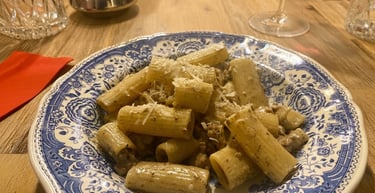 A bowl of rigatoni pasta with creamy truffle sauce and grated parmesan cheese on a blue floral plate.