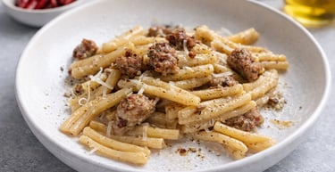 Caserecce pasta with Italian salsiccia sausage, parmesan cheese, and black pepper in a white bowl.