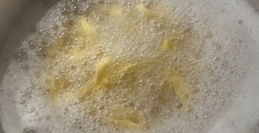 Fresh egg pasta noodles boiling in a pot of hot salted water with white starchy foam.