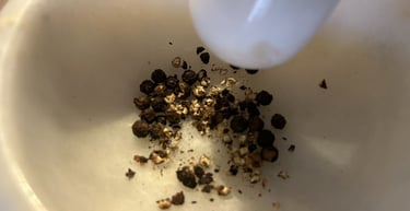 Crushing organic black peppercorns in a white marble mortar and pestle for fresh spice seasoning.
