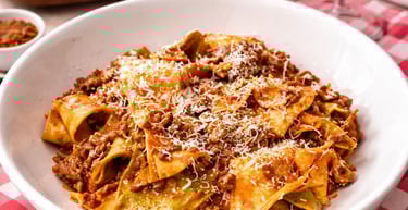 Fresh pappardelle pasta with hearty meat bolognese sauce and grated parmesan cheese.