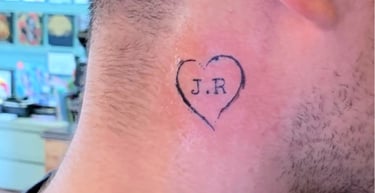 a man with a heart tattoo and the letters J.R. on his neck