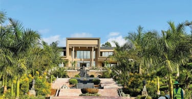 Un grand bâtiment qui est le centre climatique de Dschang avec une fontaine au milieu d'un jardin