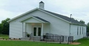 Basehor Church of Christ is a white church building with a black roof and covered porch