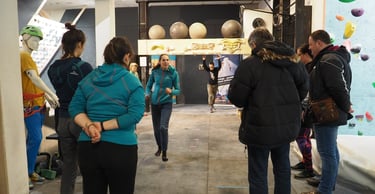 a group of people standing around a climbing wall