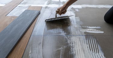 a person is using a brush to remove a floor tile