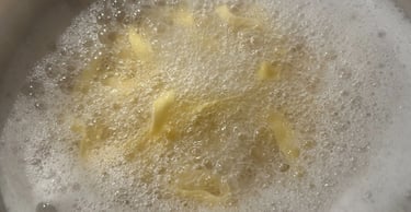 Fresh egg pasta noodles boiling in a pot of hot salted water with white starchy foam.
