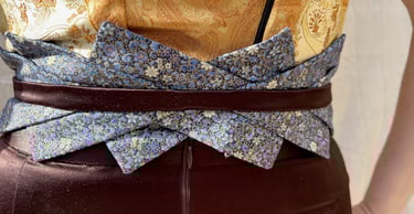 The blue floral belt of a gold brocade and brown satin evening gown