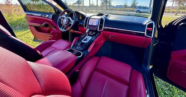 Interior of a luxury SUV with red leather seats and black trim, freshly detailed and parked under clear Florida skies