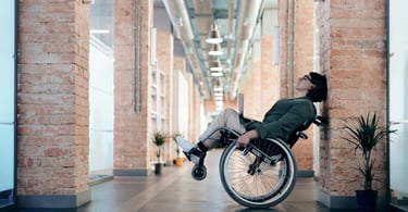 A wheelchair user rocking a wheeling in a corporate hallway